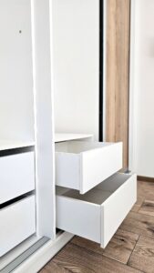 Detail vysunutých bílých zásuvek uvnitř vestavěné skříně